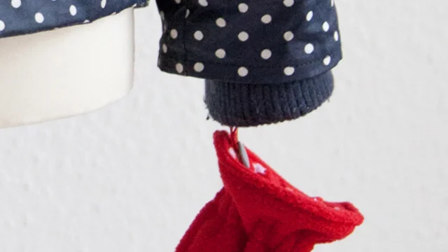 rote Kinderhandschuhe mit Befestigung an Jacke