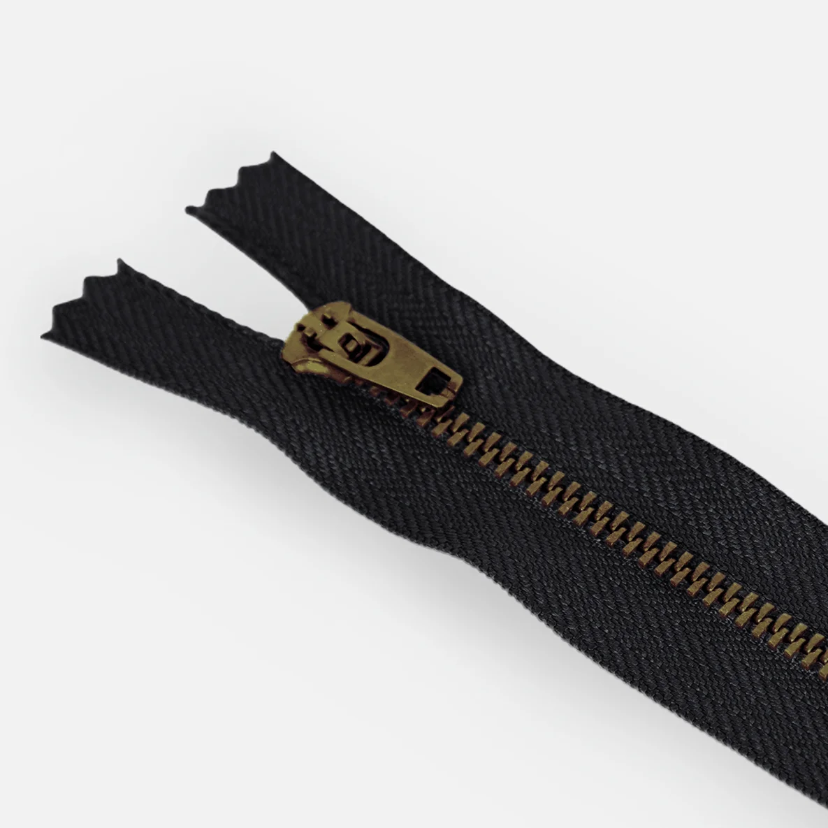Detail von Jeans-Reißverschluss in Schwarz mit Zähnchen in Messing